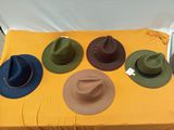 Plusieurs chapeaux sont posés sur une table recouverte d'une nappe jaune.