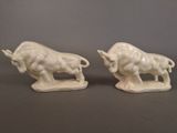 pair of white ceramic bull figurines on a gray background