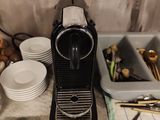 une cafetière posée sur un plan de travail, à côté d'assiettes et de tasses