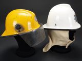 two hard hats are sitting on top of each other on a black surface