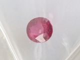 a close up of a red ruby stone in a clear bag
