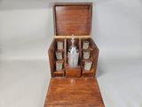 an old wooden liquor set with four glasses and a bottle in it