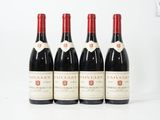quatre bouteilles de vin sont alignées sur une surface blanche