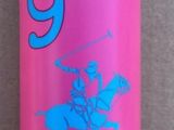 une bouteille rose avec un bouchon bleu, posée contre un mur