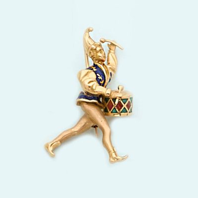a gold pin with a woman holding a drum