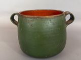 a green pot with two handles sitting on a table