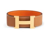 a brown and tan leather belt with a gold h buckle