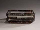 a small glass box with a handle on a white surface
