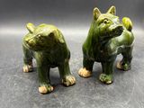 deux figurines en céramique verte représentant un chien et un chat, posées sur une table