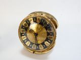 une horloge dorée au cadran noir posée sur une table blanche