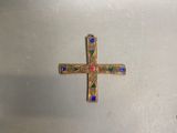 a gold cross with colorful stones on it on a white surface