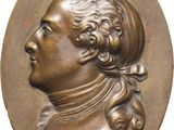 a close up of a bronze medallion of a man with long hair