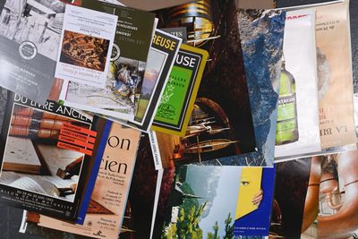 une pile de magazines posée sur une table, à côté d'une bouteille de vin