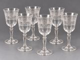 six verres à pied en verre gravé et quatre verres à vin posés sur une table