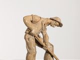 sculpture représentant un homme tenant une pelle, posée sur une surface blanche