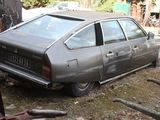 a car that is parked in the yard next to a pile of junk