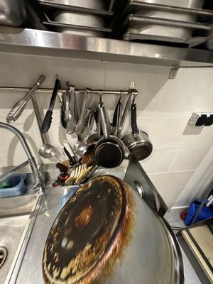 Dans une cuisine, des casseroles et des poêles sont accrochées au mur