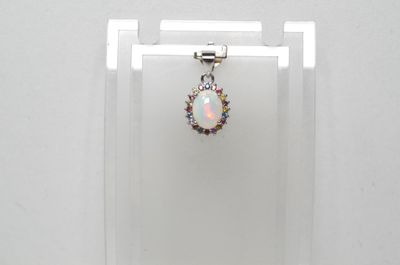Un pendentif en oplite et diamant est suspendu à un présentoir en acrylique transparent