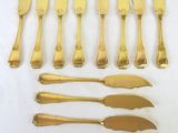 a group of gold plated knives and knives on a white surface