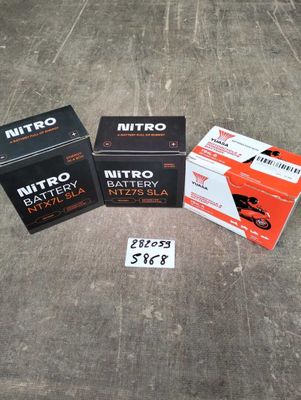 trois boîtes de piles Nitro posées par terre à côté d'une boîte de piles Nitro