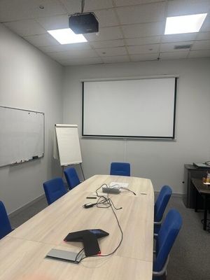 une photo d'une salle de conférence avec un écran de projection et des chaises bleues