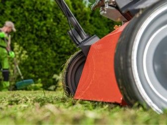 un homme en train de tondre la pelouse avec une tondeuse à gazon