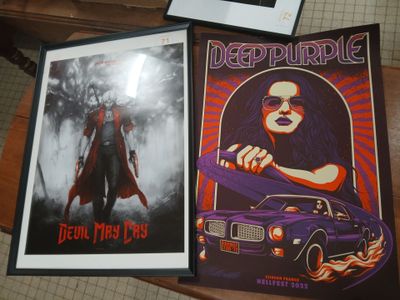 two framed posters of a woman and a car on a table