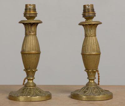 une paire de bougeoirs anciens en laiton posés sur une table en bois