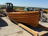un grand bateau en bois posé sur une remorque dans un parking