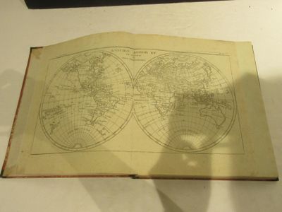 un livre ouvert, sur lequel figure une carte, posé sur une table