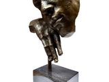 statue of a hand holding a human ' s head on a block
