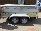 a man standing next to a trailer that has a flat bed on it