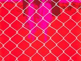 an image of a red and white photo of two people behind a chain link fence