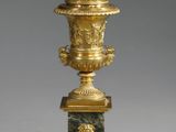 un vase doré et vert muni d'un couvercle, posé sur un socle