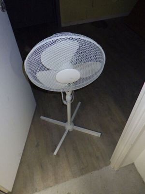 une table blanche sur laquelle est posé un ventilateur, dans un coin de la pièce