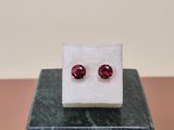 a pair of red garnet stone earrings sitting on top of a marble block