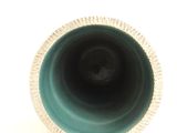 a green vase with a white rim on a white surface