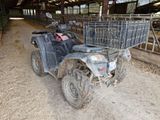 a black atv with a basket on the back of it in a barn