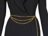 un gros plan sur le torse d'un mannequin portant un blazer noir et une ceinture à chaîne dorée