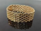 gold plated bracelet on a black surface with reflection