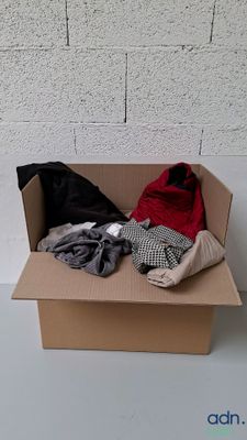 une boîte en carton remplie de vêtements posée sur une table blanche