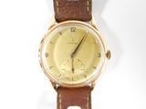 une montre en or avec un bracelet en cuir marron sur un fond blanc