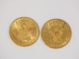 two pieces of gold coins on a white surface