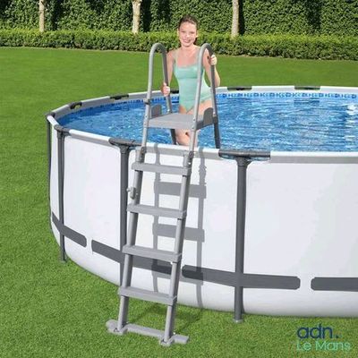 une femme assise sur une échelle près d'une piscine