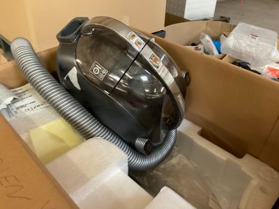 un aspirateur noir et argenté rangé dans un carton