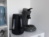 a black coffee maker sitting on top of a white shelf