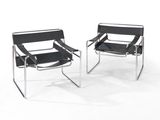 une paire de chaises en cuir noir et chrome sur fond blanc
