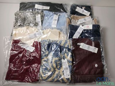 de nombreuses chemises pour hommes dans des sacs en plastique, posées sur une table