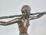 bronze statue of a woman holding a sword on top of a wooden base