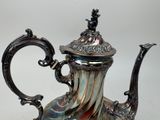 a silver tea pot with a blue and red design on it
